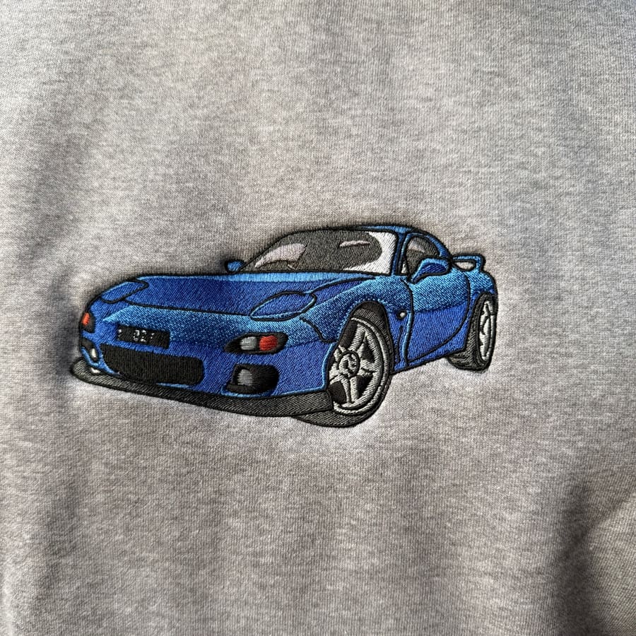 Machine embroidered blue sports car on a grey marle crewneck