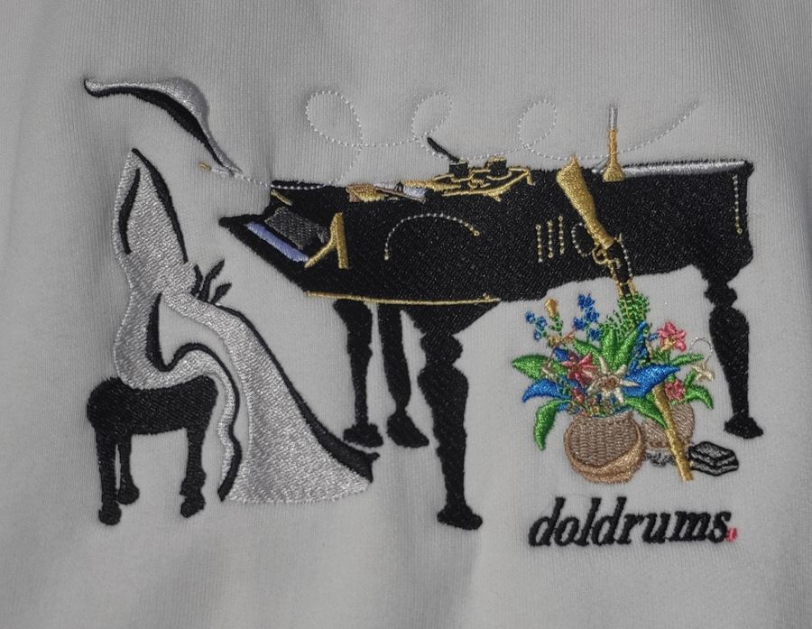 Close-up macro of a multi-colour grand piano and flowers scene embroidered on a white fleece