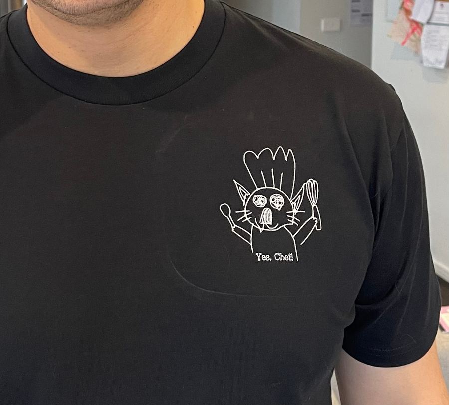Kid's cat-chef drawing embroidered in crisp white thread on a black tee
